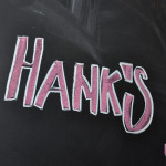 Hank's written in pink chalk with a white border on a black chalk board