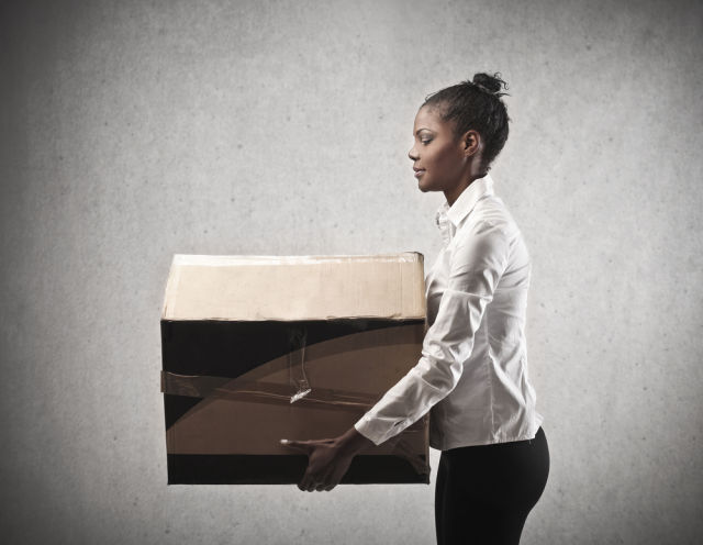 An African-American woman lifts a cardboard box