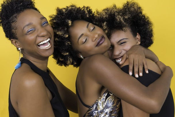Three black women embrace each other