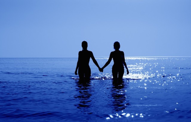 Two women holding hands in ocean water