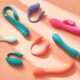 Colorful adult toys sit on coral background.
