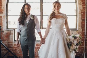 Two women holding hands in Sharpe Suiting