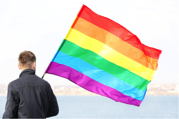 A person walking with a rainbow flag