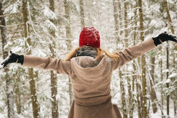 Woman with arms stretched out in the winter woods