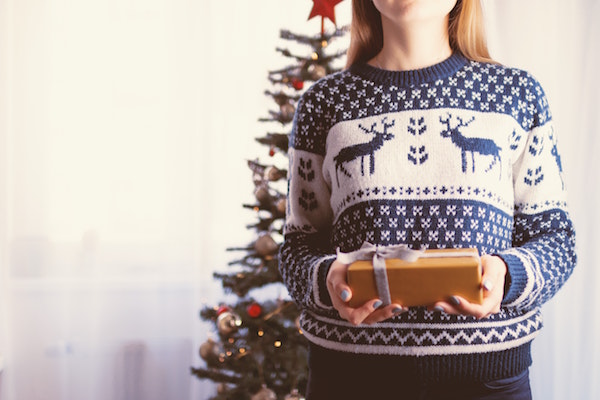 Woman in festive sweater holding a Christmas gift