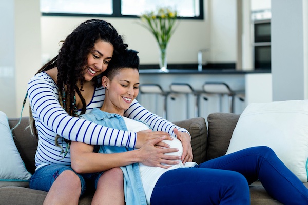 Woman sitting on sofa with pregnant partner