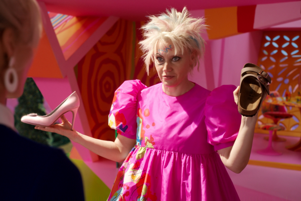 Kate McKinnon as Weird Barbie holding two shoes