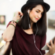 woman in black hat listening to electronic device with headphones