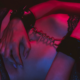 A woman in lingerie holds her handcuffed hands over her torso.