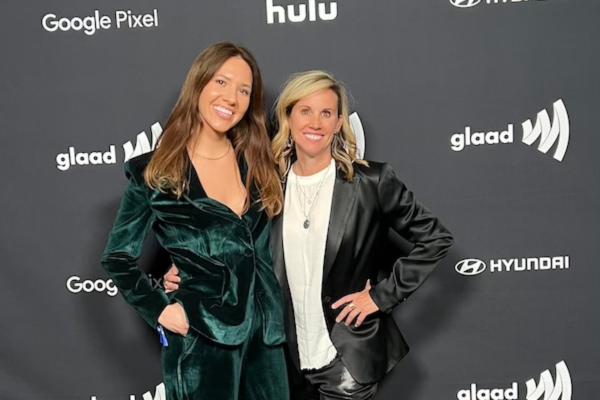 Alexandra Swarens (L) and Christin Baker (R) pose together against a step and repeat at a GLAAD event.
