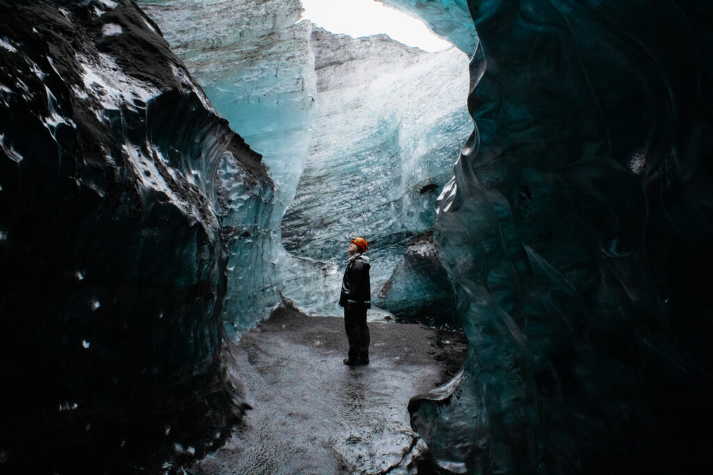 Allyssa Leaton of @TheLesbianPassport stands alone in a cave in Iceland.