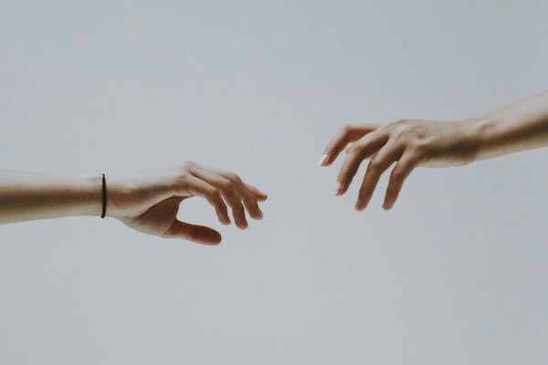 Two women's hands reach for one another, but there's too much space between the two to connect.