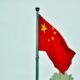 China's national flag billows in the wind in a clear sky.