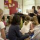 A teacher reads to a room full of elementary group children.