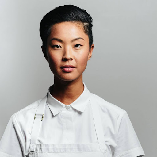 Chef Kristen Kish poses in a white chef's coat.