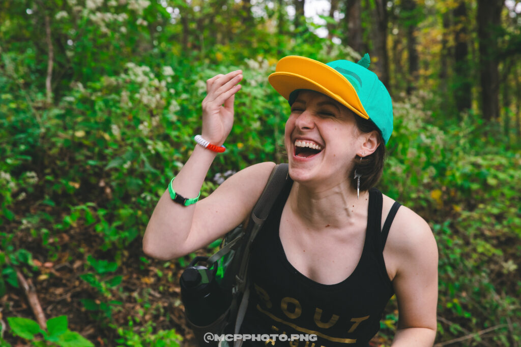 A woman laughs with joy outside.