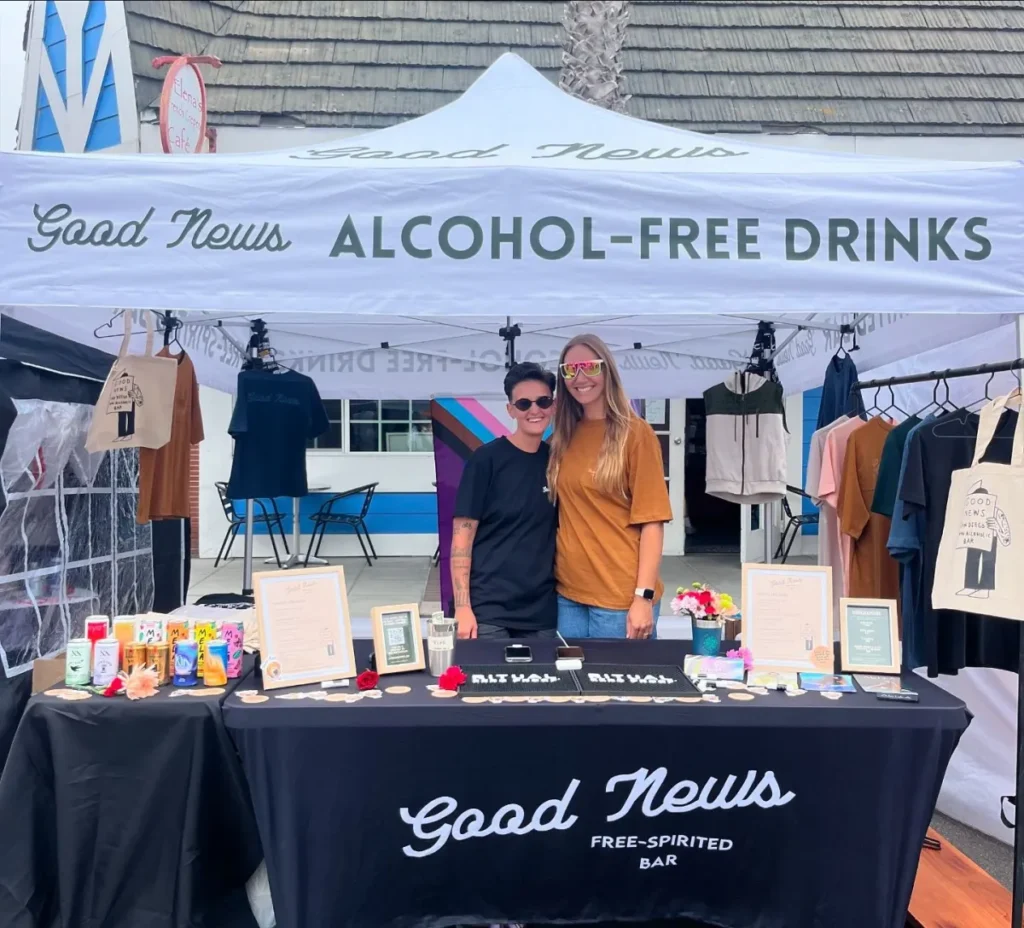 The owners of Good News in San Diego pose under a tent during a pop-up for their alcohol-free bar.