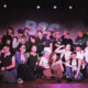 The cast of Butch Wicked pose on stage for a group photo.