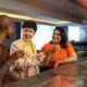 Three women smile and chat over drinks at a bar.