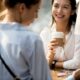 Two women sit across from one another at a table in a coffee shop.