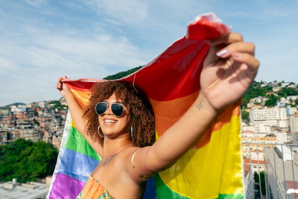 A woman wearing sunglasses holds a flag behind her head.