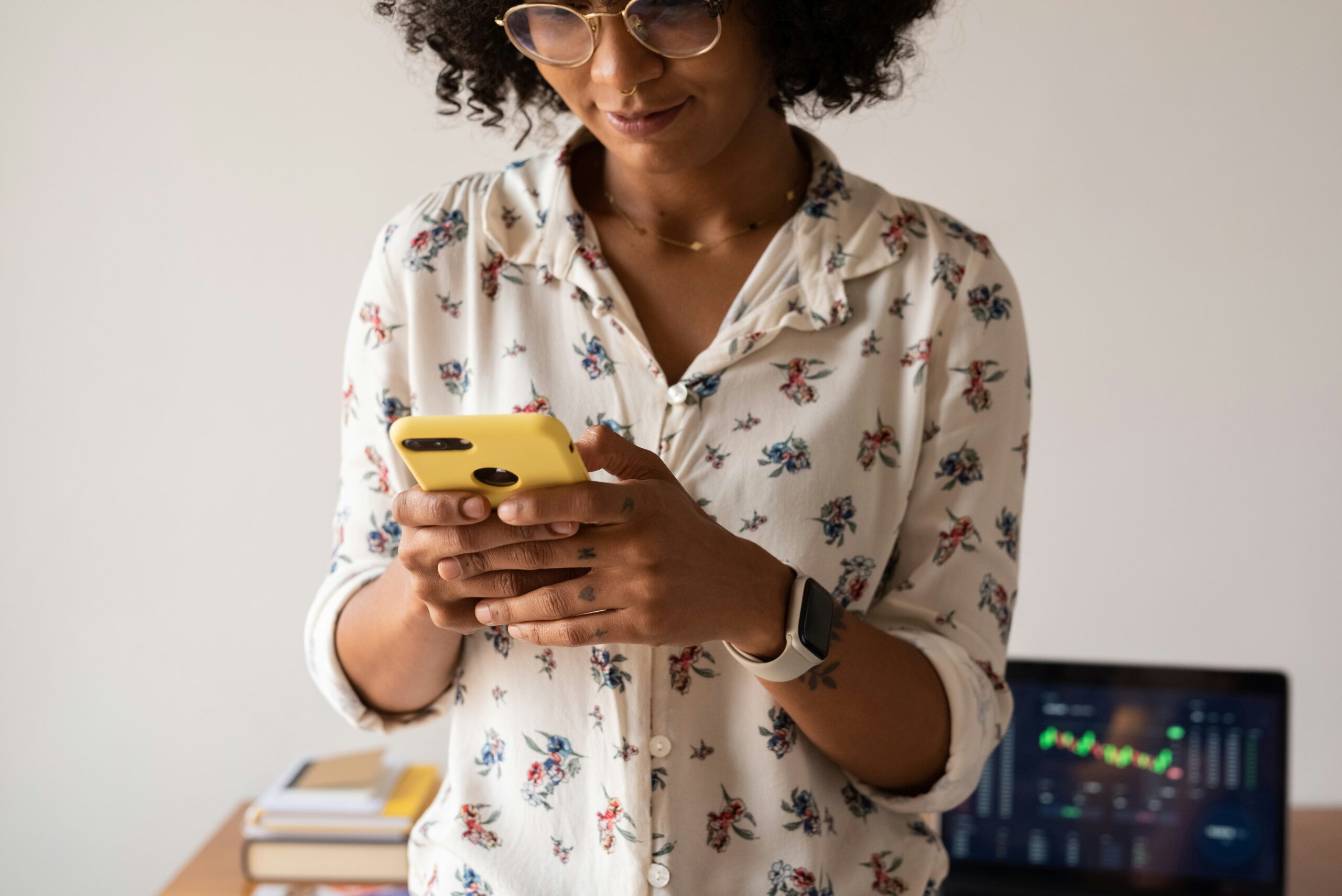 A woman holds a cell phone in her hands as she reads something on the screen.