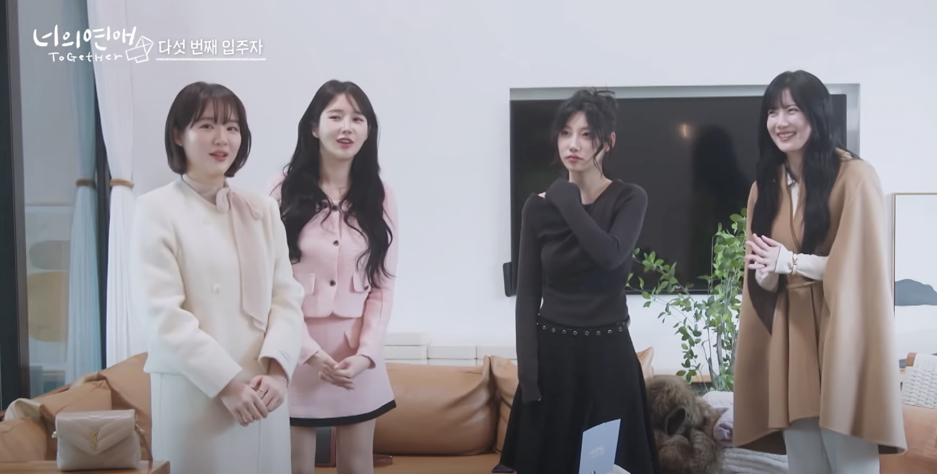 A group of four women look on curiously as a new contestant enters the house.