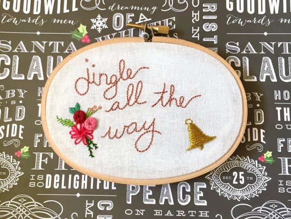 Embroidery made to look like handwriting that says jingle all the way framed in an oval hoop
