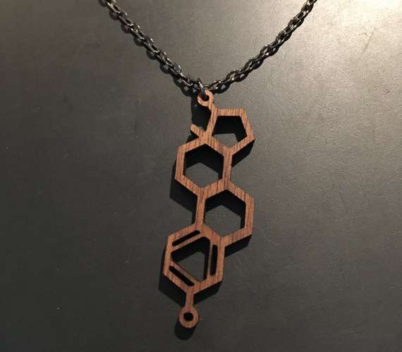 A wood-cut pendant shaped like an estrogen molecule