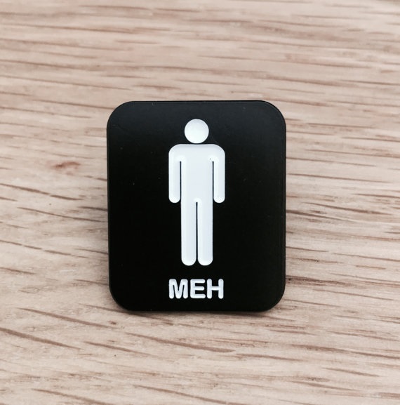 Black rectangular pin that says "meh" underneath a white silhouette of a man