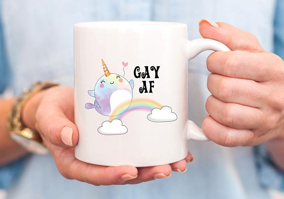 Mug with an illustration of a narwhal over a rainbow that says "gay af"