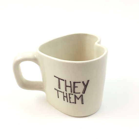 A white, heart-shaped mug that says they them